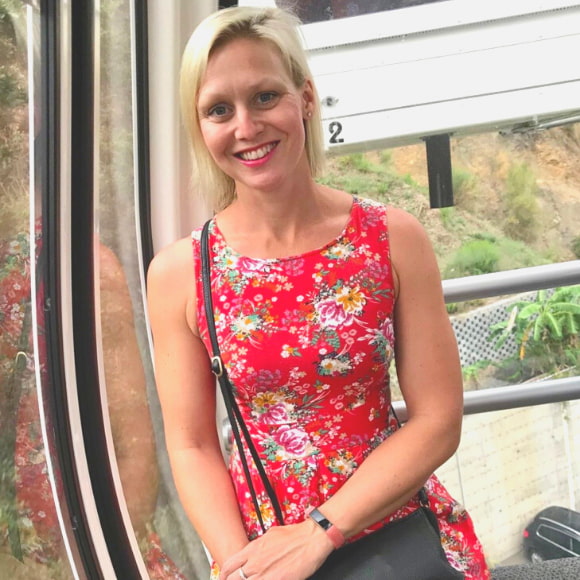 A photo of a woman with blonde hair wearing a red dress sitting in a cable car