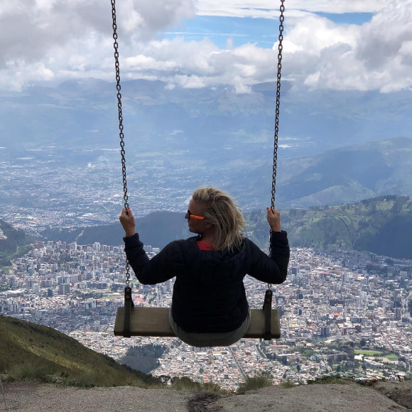 A photo of a woman sitting on a swing, overlooking a vast city